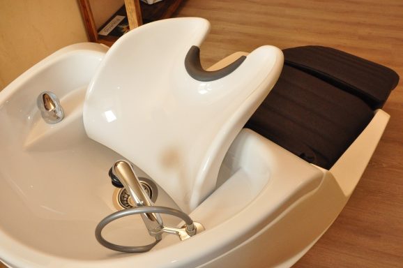 Sillón de peluquería con lavabo integrado y cómoda superficie negra.
